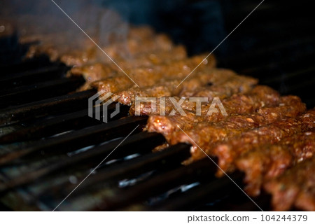 Making Spicy seekh kebabs are being grilled on burning charcoal in barbeque at a dinner party at night Making Spicy seekh kebabs are being grilled on burning charcoal in barbeque at a dinner party at night 104244379