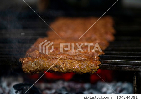 Making Spicy seekh kebabs are being grilled on burning charcoal in barbeque at a dinner party at night Making Spicy seekh kebabs are being grilled on burning charcoal in barbeque at a dinner party at night 104244381