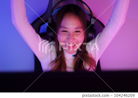 Young woman wearing headphones playing computer game 104246209