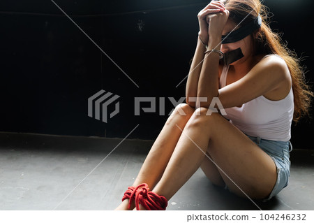 Victim of abducted woman bound wrists and feet in red rope 104246232