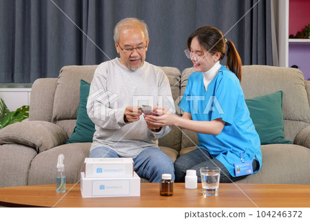 Caregiver nurse taking care of elderly grandfather sitting on sofa at home Caregiver nurse taking care of elderly grandfather sitting on sofa at home 104246372