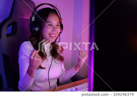 Young woman wearing headphones playing computer game 104246374