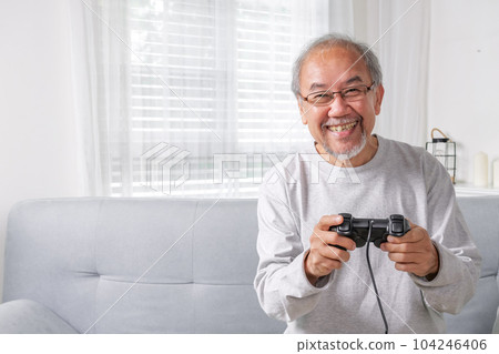 Senior elderly laughing on sofa using controller play game 104246406