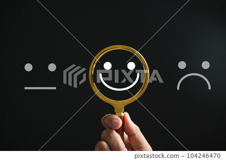 Magnifying glass reveals smiley face, finding happiness amid sadness on black. Customer satisfaction and evaluation after service survey. Magnification, satisfaction, reputation, corporate, customer 104246470