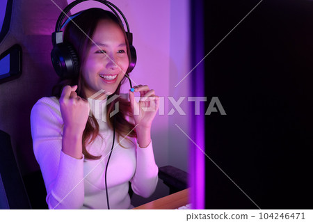 Young woman wearing headphones playing computer game 104246471