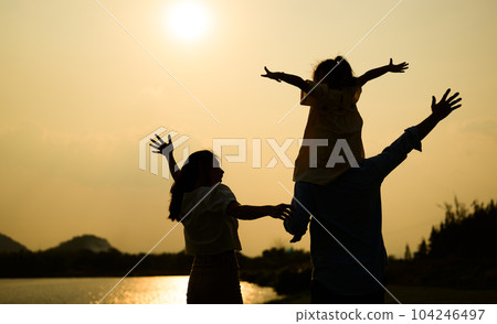 Silhouette view of happy family relaxing in park together on weekend Silhouette view of happy family relaxing in park together on weekend 104246497