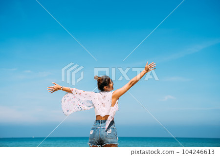 Woman standing with her arms raised enjoying with wonderful view of beach Woman standing with her arms raised enjoying with wonderful view of beach 104246613