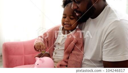 Daughter and father saving money putting coin of cash into ceramic piggy bank Daughter and father saving money putting coin of cash into ceramic piggy bank 104246817