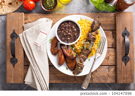Beef kebab with rice, beans and fried plantains 104247896