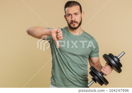 Upset tired athlete sportive man showing thumbs down sign gesture disapproval, dissatisfied, dislike 104247996