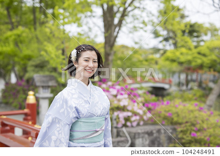 A woman in a kimono strolling through the fresh greenery 104248491