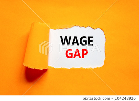 Wage gap symbol. Concept words Wage gap on beautiful white paper on a beautiful orange background. Business, support and wage gap concept. Copy space. Wage gap symbol. Concept words Wage gap on beautiful white paper on a beautiful orange background. Business, support and wage gap concept. Copy space. 104248926