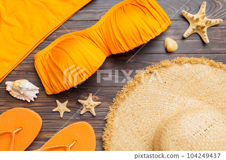 Woman swimwear and beach accessories flat lay top view on colored background Summer travel concept. bikini swimsuit, straw hat and seasheels. Copy space Top view 104249437