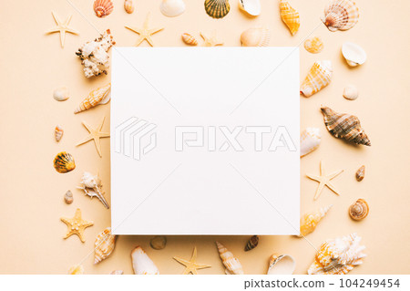 Summer time concept with blank greeting card and blank white paper on colored background. Seashells from ocean shore in the shape of frame separated with space for text top view Summer time concept with blank greeting card and blank white paper on colored background. Seashells from ocean shore in the shape of frame separated with space for text top view 104249454