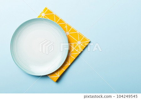 Top view on colored background empty round blue plate on tablecloth for food. Empty dish on napkin with space for your design 104249545