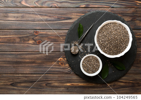 Chia seeds in bowl and spoon on colored background. Healthy Salvia hispanica in small bowl. Healthy superfood Chia seeds in bowl and spoon on colored background. Healthy Salvia hispanica in small bowl. Healthy superfood 104249565
