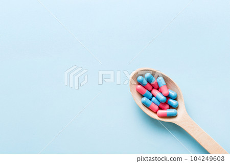 Vitamin capsules in a spoon on a colored background. Pills served as a healthy meal. Red soft gel vitamin supplement capsules on spoon Vitamin capsules in a spoon on a colored background. Pills served as a healthy meal. Red soft gel vitamin supplement capsules on spoon 104249608