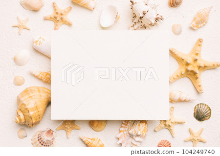 Summer time concept with blank greeting card and blank white paper on colored background. Seashells from ocean shore in the shape of frame separated with space for text top view Summer time concept with blank greeting card and blank white paper on colored background. Seashells from ocean shore in the shape of frame separated with space for text top view 104249740
