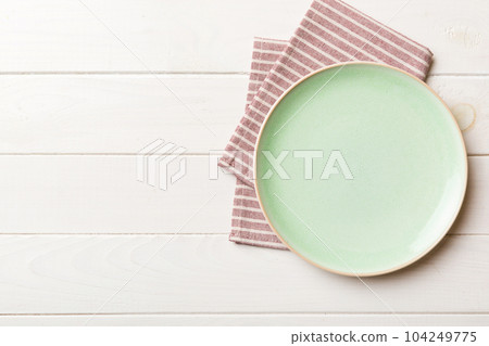 Top view on colored background empty round green plate on tablecloth for food. Empty dish on napkin with space for your design 104249775