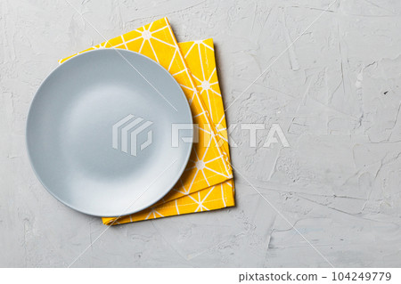 Top view on colored background empty round gray plate on tablecloth for food. Empty dish on napkin with space for your design Top view on colored background empty round gray plate on tablecloth for food. Empty dish on napkin with space for your design 104249779
