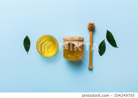 Honey jar with wooden honey dipper on white background top view with copy space. Delicious honey bottle Honey jar with wooden honey dipper on white background top view with copy space. Delicious honey bottle 104249785