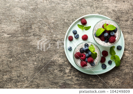 Healthy breakfast or morning with chia seeds vanilla pudding raspberry and blueberry berries on table background, vegetarian food, diet and health concept. Chia pudding with raspberry and blueberry Healthy breakfast or morning with chia seeds vanilla pudding raspberry and blueberry berries on table background, vegetarian food, diet and health concept. Chia pudding with raspberry and blueberry 104249809