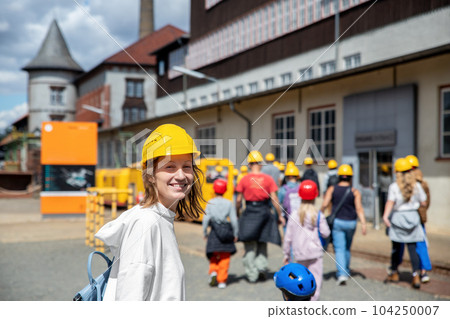 Portrait happy woman tourist wear yellow safety helmet equipment at Rammelsberg Unesco Mine trip entrance group tour. Tourism at industrial miner area Goslar Harz, Germany. Extreme mountain adventure Portrait happy woman tourist wear yellow safety helmet equipment at Rammelsberg Unesco Mine trip entrance group tour. Tourism at industrial miner area Goslar Harz, Germany. Extreme mountain adventure 104250007