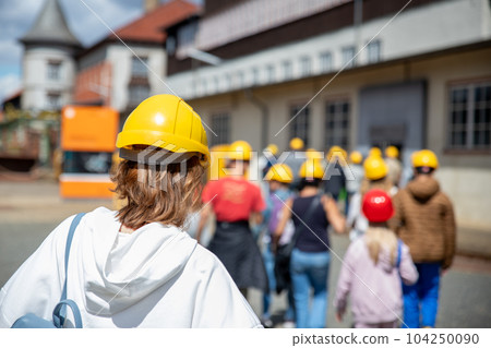Back view woman tourist wear yellow safety helmet equipment at Rammelsberg Unesco Mine trip entrance group tour. Tourism at industrial miner area Goslar Harz, Germany. Extreme mountain adventure 104250090
