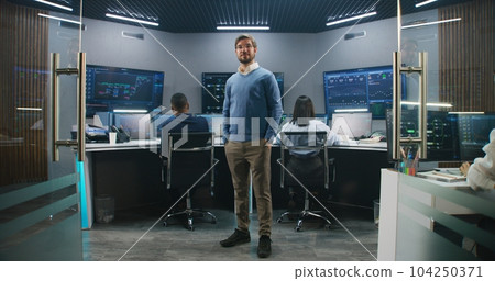 IT scientist smiles and stands in monitoring room 104250371