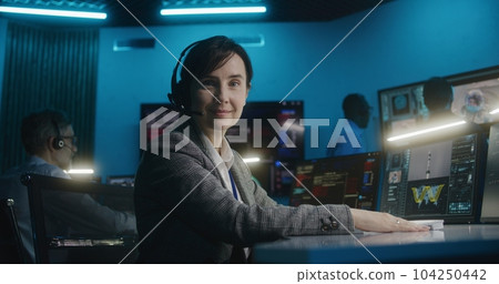 Female flight control worker monitors space mission, looks at camera 104250442