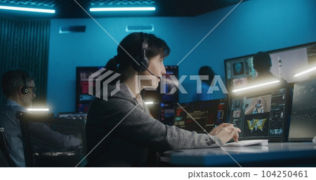 Female flight control worker monitors space mission, looks at camera 104250461