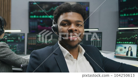 African American trader in headset looks at camera African American trader in headset looks at camera 104250613