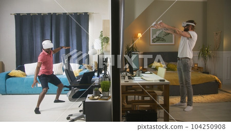 Neighbours in VR headsets play video games in different rooms or apartments 104250908