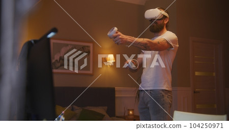 Man plays game using VR headset and controllers Man plays game using VR headset and controllers 104250971