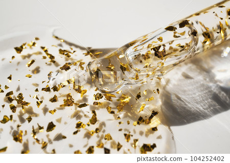 Pipette and drop of cosmetic product with gold particles, selective focus Pipette and drop of cosmetic product with gold particles, selective focus 104252402