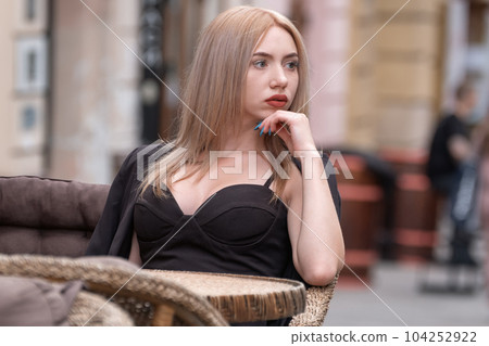 Thoughtful young attractive business woman sitting at table in cafe in black suit and waiting. 104252922