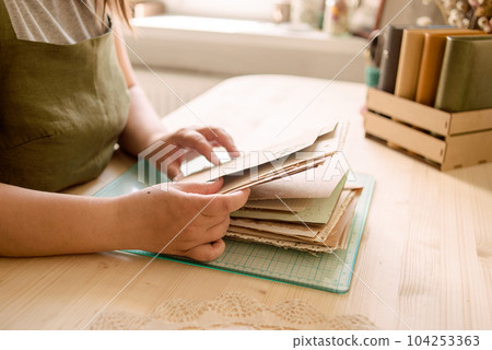 A creative person makes a scrapbook or notebook in their office. Handmade, exclusive. High quality photo A creative person makes a scrapbook or notebook in their office. Handmade, exclusive. High quality photo 104253363