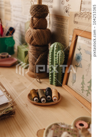 Creative Corner. Details on a wooden work table, scissors, thread, fabrics. . High quality photo 104253365