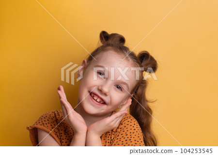 Portrait of young excited crazy smiling child girl holding hands isolated on yellow background. High quality photo 104253545