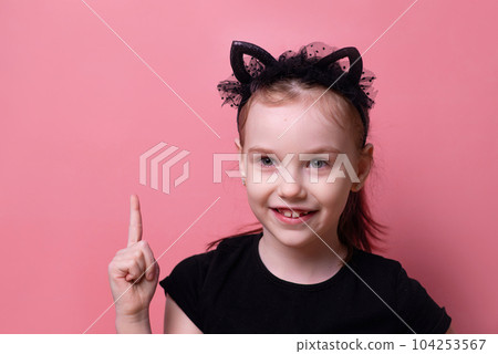 Portrait of a GIRL in a black t-shirt with a thumbs up, looking up and thinking, isolated on a pink studio background. High quality photo 104253567
