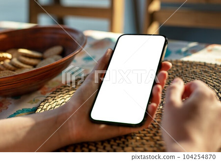 Hand using smartphone screen mock-up at dinner table, ordering food delivery 104254870