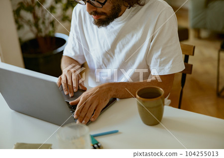 Close up of man freelancer sitting at home and working on laptop online. Remote work concept Close up of man freelancer sitting at home and working on laptop online. Remote work concept 104255013