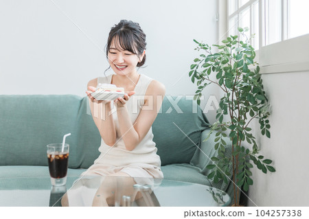 A woman who eats a snack / snack cake at home A woman who eats a snack / snack cake at home 104257338