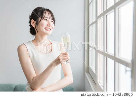 A woman who drinks champagne, carbonated water, and carbonated drinks during the day at home 104258900