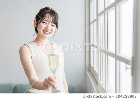 A woman who makes a toast by drinking champagne, carbonated water, and carbonated drinks in the daytime at home A woman who makes a toast by drinking champagne, carbonated water, and carbonated drinks in the daytime at home 104258902