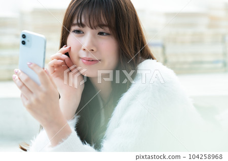 一名躺下並使用智能手機的年輕女子 104258968