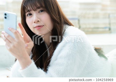 一名躺下並使用智能手機的年輕女子 104258969