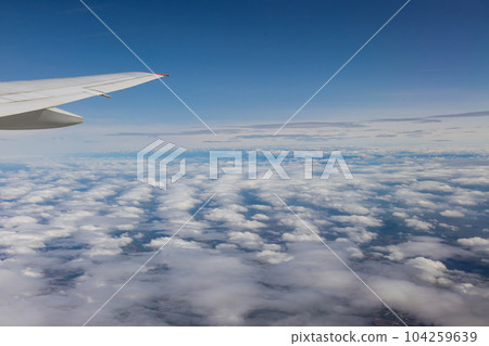 Airplane window captivated by stunning view of Earth majestic landscapes vastness of cloudy sky. 104259639