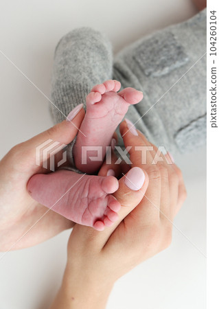 The palms of the father, the mother are holding the foot of the newborn baby on white background. Feet of the newborn on the palms of the parents. Photography of a child's toes, heels and feet. 104260104