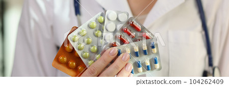 Doctor woman hand holding many blisters with pills closeup 104262409